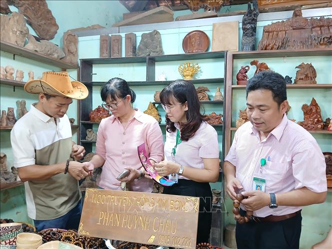 Cán bộ Ngân hàng chính sách xã hội khảo sát mô hình sản xuất kinh doanh điêu khắc gỗ của anh Phan Huỳnh Châu ở Tổ dân phố Phước Trung, phường Hội An (Đà Nẵng). Ảnh: Mỹ Hà - TTXVN