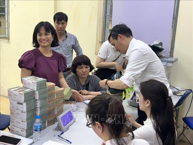 Người dân vui vẻ nhận tiền đền bù giải phóng mặt bằng tại Nhà sinh hoạt cộng đồng số 5 phường Hồng Hà. Ảnh: Quốc Lũy - TTXVN