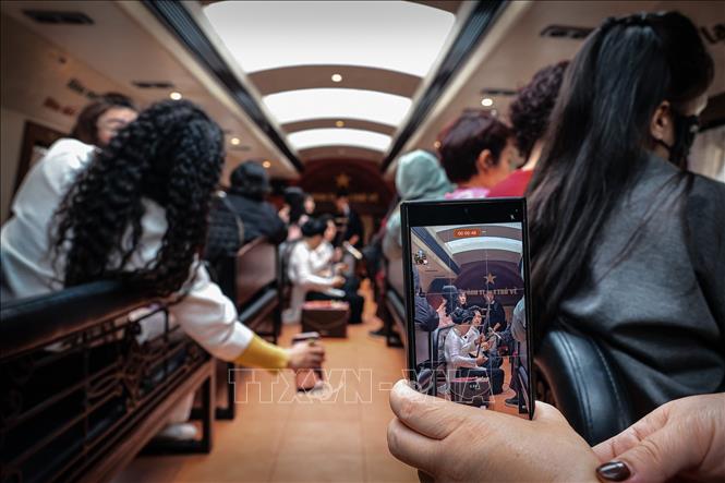 Du khách ghi hình tiết mục biểu diễn trên tàu bằng điện thoại thông minh, thể hiện sự kết hợp giữa trải nghiệm thực tế và lan tỏa văn hóa trên nền tảng số. Ảnh: Phạm Tuấn Anh - TTXVN