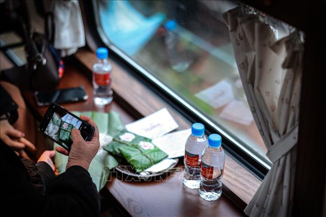 Du khách chụp ảnh món quà truyền thống bên ô cửa tàu, lưu giữ những khoảnh khắc mang đậm dấu ấn văn hóa Hà Nội. Ảnh: Phạm Tuấn Anh - TTXVN