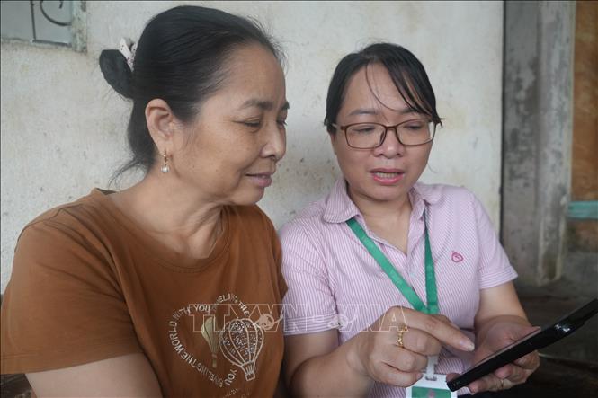 Chỉ cần chiếc điện thoại thông minh, chị Lê Thị Như, thôn Hoạch thôn, xã Yên Định có thể trả tiền lãi, gốc khoản vay NHCSXH mọi lúc, mọi nơi, kể cả ngoài giờ hành chính, giúp tiết kiệm thời gian, công sức đi lại như trước đây. Ảnh: Khiếu Tư-TTXVN 
