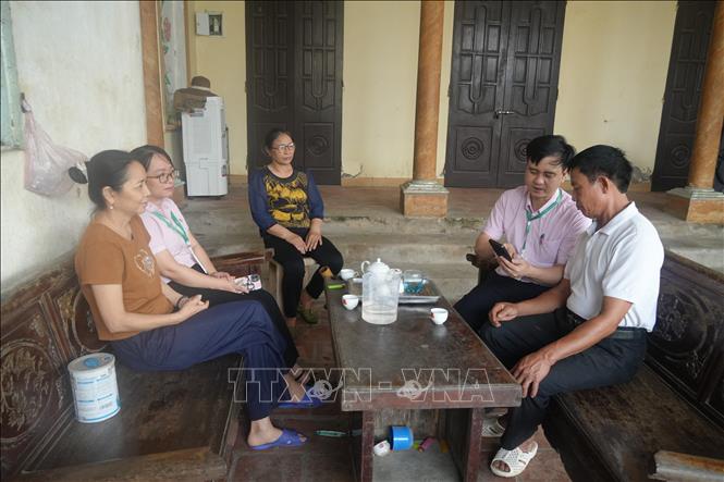 Cán bộ Phòng giao dịch NHCSXH Yên Định trực tiếp hỗ trợ, hướng dẫnkhách hàng cài đặt dịch vụ ngay tại nhà, giúp người dân tiếp cận và sử dụng thành thạo các tính năng cơ bản của ứng dụng. Ảnh: Khiếu Tư-TTXVN 