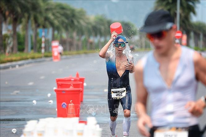 Vận động viên tham gia nội dung chạy bộ tại giải ba môn phối hợp tranh thủ làm mát cơ thể bằng nước trong điều kiện thời tiết nắng nóng, trên cung đường thi đấu ven biển. Ảnh: Phạm Tuấn Anh - TTXVN