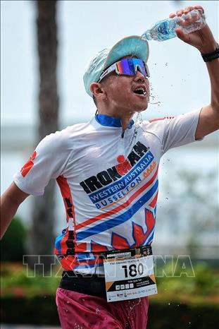 Vận động viên sử dụng nước làm mát cho những bước chạy cuối cùng trước khi về đích. Ảnh: Phạm Tuấn Anh - TTXVN