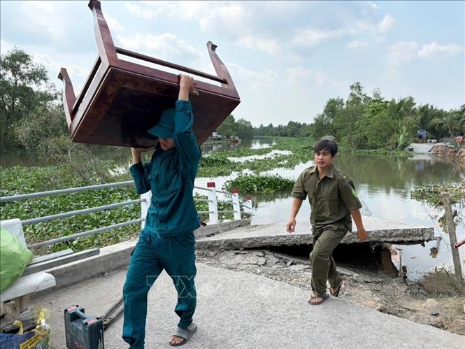 Lực lượng chức năng hỗ trợ người dân bị ảnh hưởng sạt lở di dời đồ đạc. Ảnh: Công Trí-TTXVN
