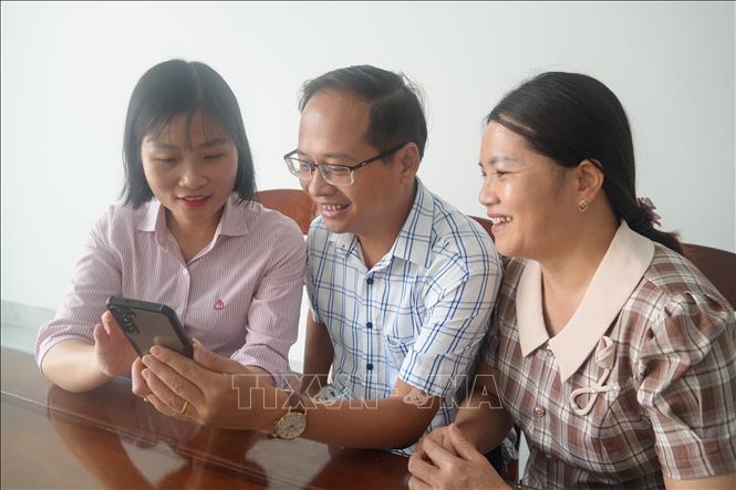 Cán bộ Phòng giao dịch NHCSXH Thiệu Hóa đến tận nhà hướng dẫn khách hàng cài đặt và thực hiện các thao tác sử dụng dịch vụ VBSP SmartBanking. Ảnh: Khiếu Tư-TTXVN