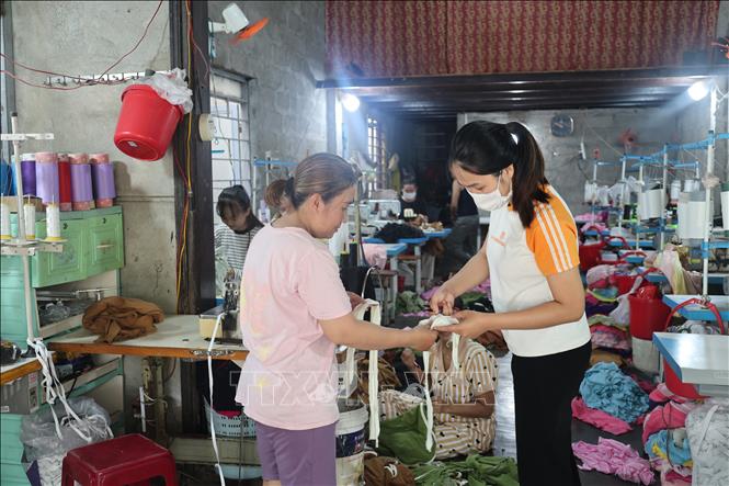 Sau khi lên bờ định cư tại Tổ dân phố Lại Tân, phường Dương Nỗ, chị Võ Thị Lý (bên trái) xây dựng cơ sở may tạo công ăn việc làm cho nhiều người dân nơi đây. Ảnh: Hải Âu-TTXVN.