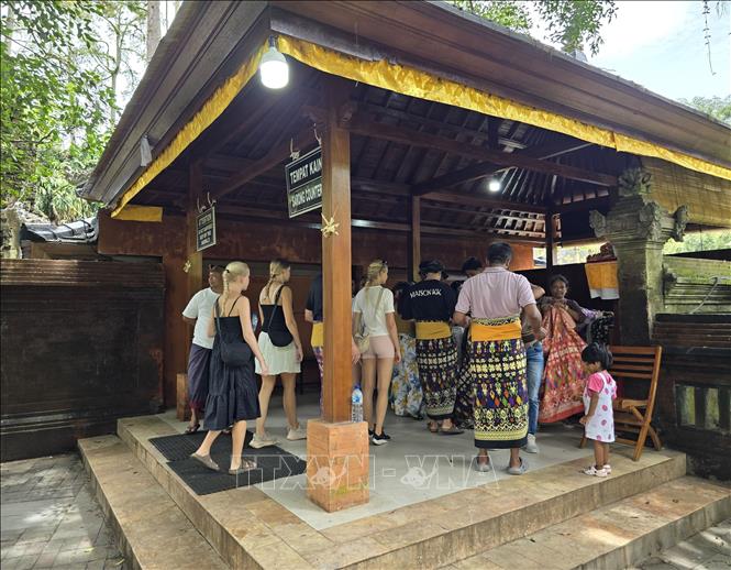 Trước khi vào đền, du khách thực hiện nghi thức quấn sarong để thể hiện sự tôn kính với thần linh
Ảnh: Lê Minh Hưởng - PvTTXVN tại Indonesia