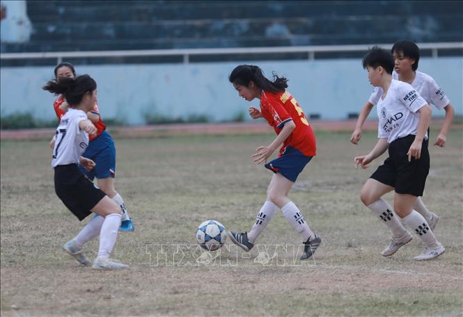 Cầu thủ đội nữ Công an tỉnh Lạng Sơn (áo đỏ) tìm cách vượt qua sự đeo bám của các cầu thủ nữ cụm xã Thất Khê (áo trắng) trong trận bóng chiều ngày khai mạc Giải. Ảnh: Anh Tuấn – TTXVN