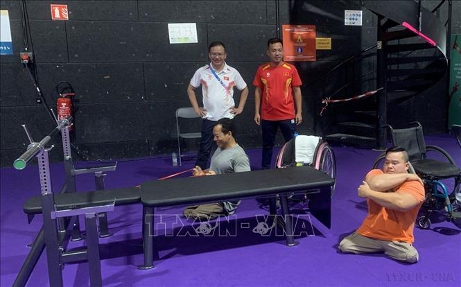 Trưởng đoàn Thể thao người khuyết tật Việt Nam dự Paralympic Paris 2024 Nguyễn Hồng Minh (áo trắng) động viên các lực sỹ của đội tuyển cử tạ người khuyết tật Việt Nam tập luyện. Ảnh: TTXVN phát
