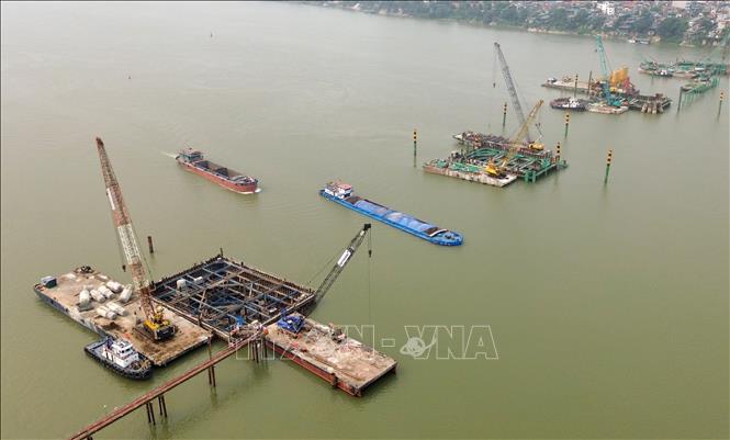 Tranh thủ thời tiết thuận lợi đầu năm, các nhà thầu thi công cầu Trần Hưng Đạo vượt sông Hồng đang huy động tối đa nhân lực, máy móc, tổ chức nhiều mũi thi công song song, quyết tâm bám “đường găng” tiến độ để đưa công trình về đích đúng cam kết. Ảnh: Quốc Khánh - TTXVN