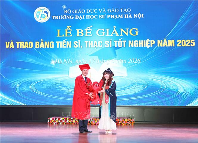 Đại diện tân Tiến sĩ, Thạc sĩ tặng hoa cảm ơn nhà trường. Ảnh: Thanh Tùng - TTXVN