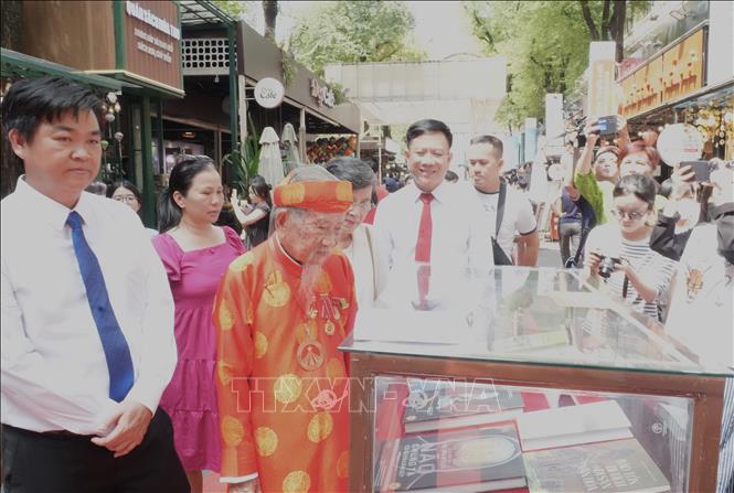 Nhà nghiên cứu Nguyễn Đình Tư cùng các đại biểu tham quan triển lãm. Ảnh: Hữu Duyên - TTXVN