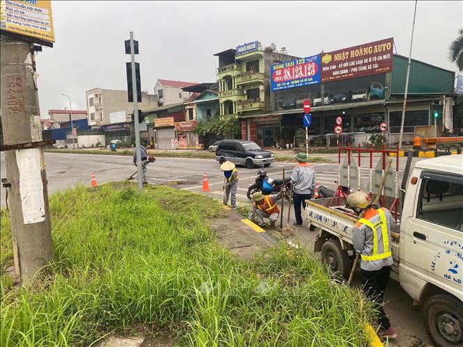 Thu dọn rác, cắt cỏ đảm bảo mỹ quan đô thị. Ảnh: Nguyễn Thắng - TTXVN