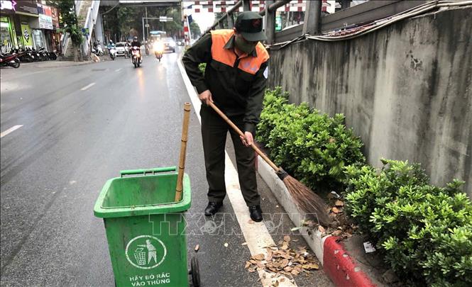 Thu dọn rác, vệ sinh môi trường bên hành lang các cầu vượt cạn, đảm bảo mỹ quan đô thị. Ảnh: Nguyễn Thắng - TTXVN