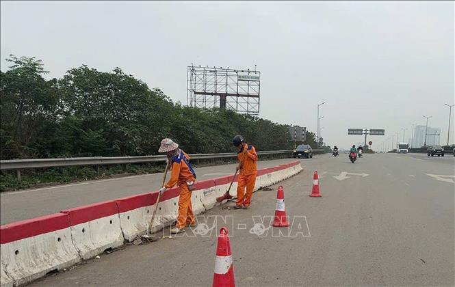 Thu dọn, vệ sinh môi trường ở các giải phân cách, đảm bảo mỹ quan đô thị. Ảnh: Nguyễn Thắng - TTXVN
