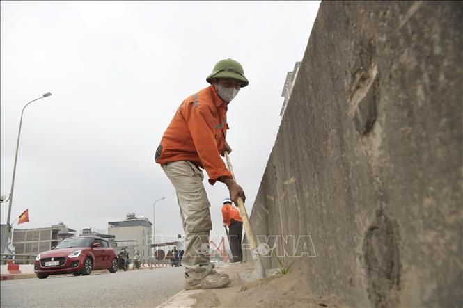 Vệ sinh, thu dọn cát bụi trên mặt đường. Ảnh: Nguyễn Thắng - TTXVN