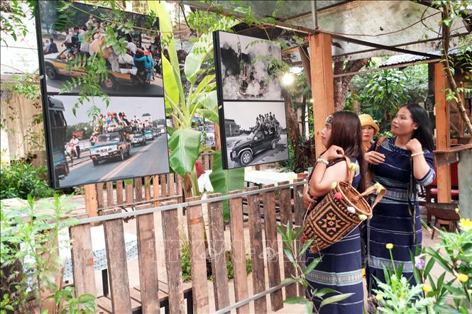 Các nghệ sĩ người dân tộc K'Ho tranh thủ xem ảnh triển lãm trước giờ khai mạc. Ảnh Chu Quốc Hùng - TTXVN