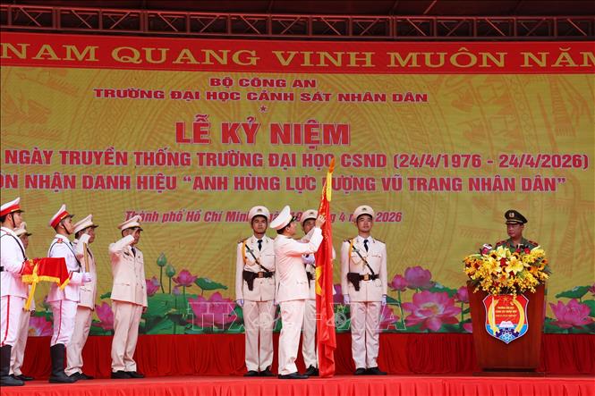 Đại tướng Lương Tam Quang, Ủy viên Bộ Chính trị, Bộ trưởng Bộ Công an gắn huy hiệu Anh hùng Lực lượng vũ trang nhân dân lên lá cờ truyền thống của Trường Đại học Cảnh sát nhân dân. Ảnh: Hồng Đạt - TTXVN