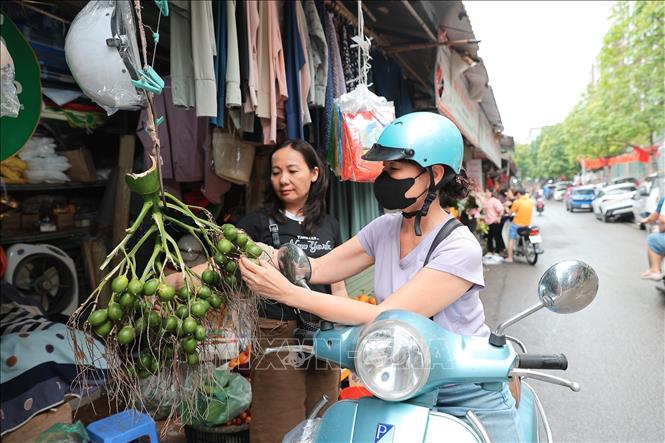 Người dân Thủ đô chọn mua hoa và bánh trôi, bánh chay trong dịp Tết Hàn thực, gửi gắm mong ước bình an và may mắn cho gia đình. Ảnh: Lê Đông - TTXVN
