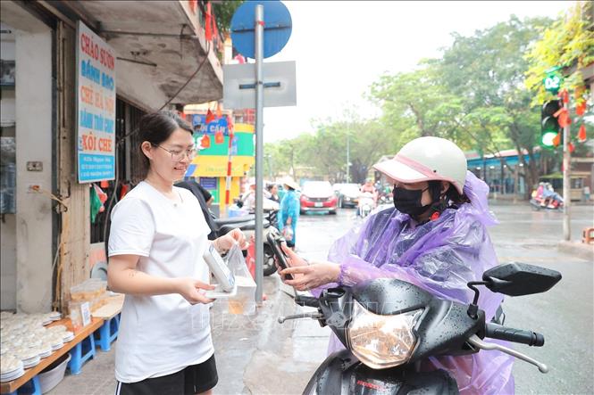 Người dân mua bánh trôi, bánh chay và thanh toán nhanh chóng bằng mã QR. Ảnh: Lê Đông - TTXVN
