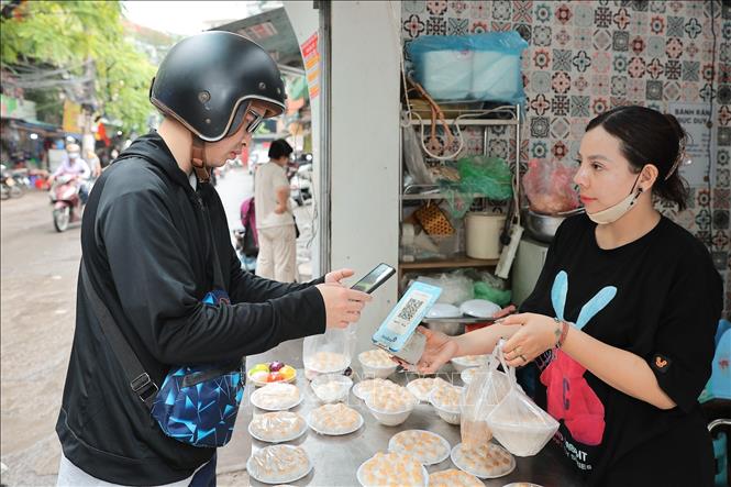 Không cần tiền mặt, người mua dễ dàng quét QR để thanh toán khi mua bánh. Ảnh: Lê Đông - TTXVN