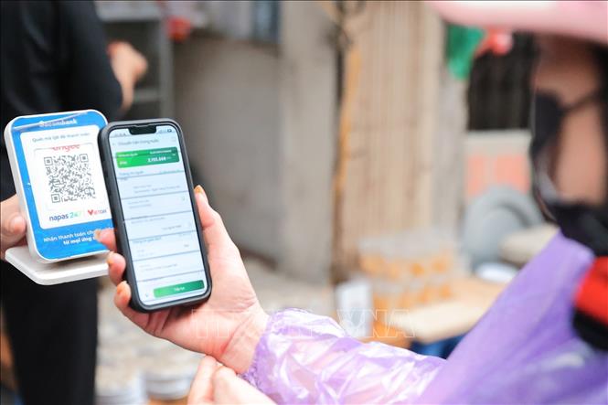 Người dân mua bánh trôi, bánh chay và thanh toán nhanh chóng bằng mã QR. Ảnh: Lê Đông - TTXVN