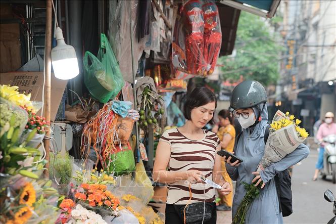 Tiểu thương linh hoạt áp dụng thanh toán QR code, phục vụ khách hàng thuận tiện hơn. Ảnh: Lê Đông - TTXVN