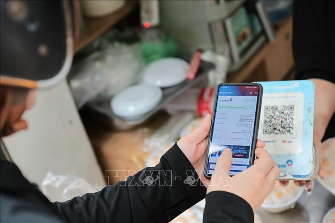 Không cần tiền mặt, người mua dễ dàng quét mã QR để thanh toán khi mua bánh truyền thống. Ảnh: Lê Đông - TTXVN