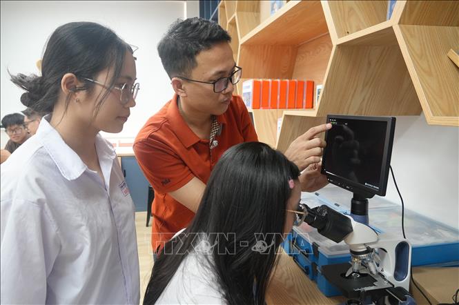 Thầy Lê Nhất Trường Tuấn, giáo viên Vật lý Trường THPT Hàm Rồng hướng dẫn các em học sinh sử dụng các thiết bị tại phòng học STEM của nhà trường. Ảnh: Khiếu Tư - TTXVN 

