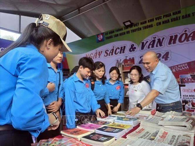 Đại diện Trung tâm Dịch vụ Truyền thông, Chi nhánh Nhà Xuất bản Thông tấn giới thiệu sách và các ấn phẩm của Thông tấn Xã Việt Nam đến những người yêu sách tại tỉnh Cà Mau (2024). Ảnh: Kim Há-TTXVN