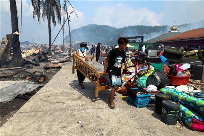 Người dân di chuyển đồ đạc sau vụ hỏa hoạn tại làng chài ven biển ở bang Sabah, trên đảo Borneo, Malaysia ngày 19/4/2026. Ảnh: THX/TTXVN