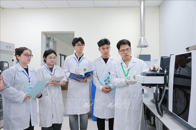 Sinh viên Khoa Tài nguyên và môi trường được giảng viên trực tiếp hướng dẫn sử dụng Máy quang phổ hấp thụ nguyên tử dùng để kiểm tra chất lượng nước, thực phẩm, dược phẩm, đất, môi trường. Ảnh: Lê Đông - TTXVN