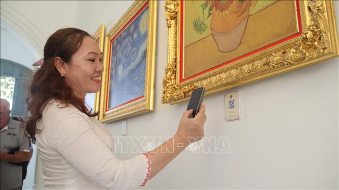 Visitors use QR code to learn about the paintings. VNA Photo: Huỳnh Sơn 