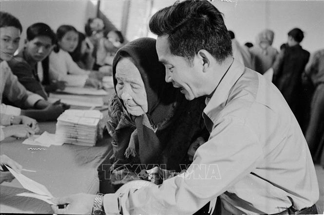 Ngày 25/4/1976, trên 23 triệu cử tri của nước Việt Nam thống nhất đã nô nức đi bầu cử. Đây thực sự là ngày hội lớn của toàn dân Việt Nam. Trong ảnh: Cụ Lê Thị Dưỡng (86 tuổi, TP.Huế), già yếu vẫn nhờ người cõng đến hòm phiếu tham gia bầu cử đại biểu Quốc hội thống nhất (25/4/1976). Ảnh: Sỹ Thái – TTXVN

