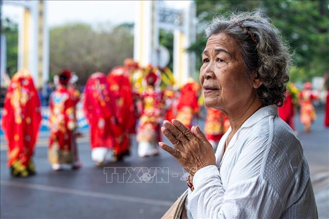 Người dân bên đường thành kính chắp tay khi đoàn rước cung nghinh Thánh Mẫu đi qua đường Trần Hưng Đạo. Ảnh: Vân Chi/TTXVN phát
