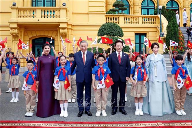 Tổng Bí thư, Chủ tịch nước Tô Lâm và Phu nhân cùng Tổng thống Hàn Quốc Lee Jae Myung và Phu nhân với thiếu nhi Thủ đô Hà Nội tại lễ đón. Ảnh: Thống Nhất – TTXVN