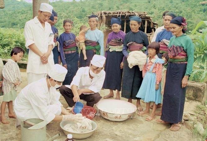 Nhân viên y tế của Trung tâm Y tế huyện Ngọc Lặc (Thanh Hóa) hướng dẫn đồng bào dân tộc Mường cách tẩm màn hóa chất phòng chống sốt rét. Ảnh: Trần Thiêm - TTXVN