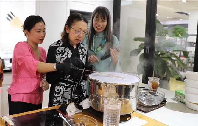 Bà Varaporn (giữa), phu nhân Phó Thủ tướng kiêm Ngoại trưởng Thái Lan Sihasak Phuangketkeow, thích thú trải nghiệm tráng bánh cuốn. Ảnh: Đỗ Sinh – PV TTXVN tại Thái Lan