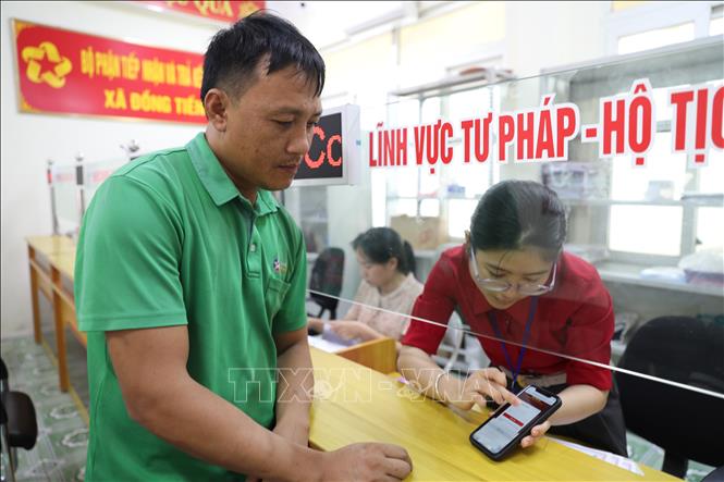 Cán bộ Trung tâm phục vụ hành chính công xã Đồng Tiến hướng dẫn người dân các thủ tục trên VNID để xử lý hồ sơ. Ảnh: Khiếu Tư - TTXVN
