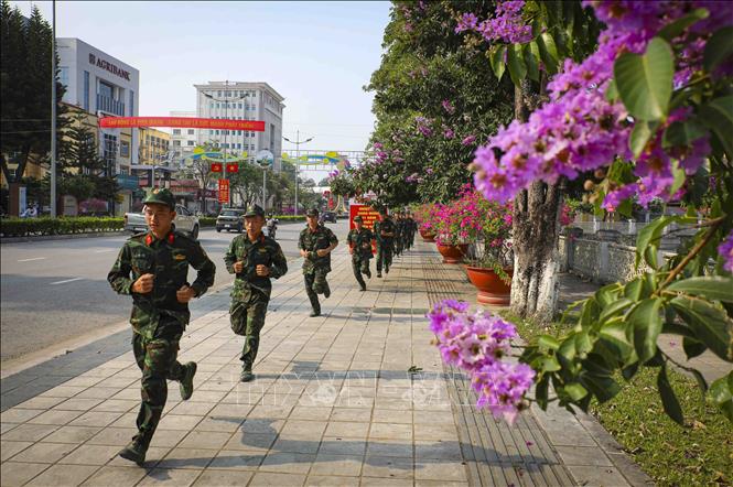 Chiến sĩ luyện tập trên tuyến phố rợp sắc hoa bằng lăng. Ảnh: Xuân Tư - TTXVN