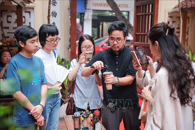 Nghệ nhân hướng dẫn kỹ thuật khảm vỏ trứng và xử lý bề mặt  để hoàn thiện sản phẩm sơn mài cho người tham gia trải nghiệm. Ảnh: Phạm Tuấn Anh - TTXVN