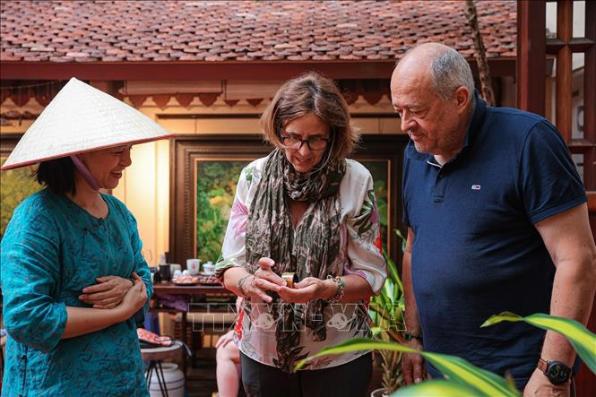 Du khách nước ngoài tìm hiểu và trải nghiệm sản phẩm sơn ta, thể hiện sức hút của văn hóa truyền thống Việt Nam. Ảnh: Phạm Tuấn Anh - TTXVN