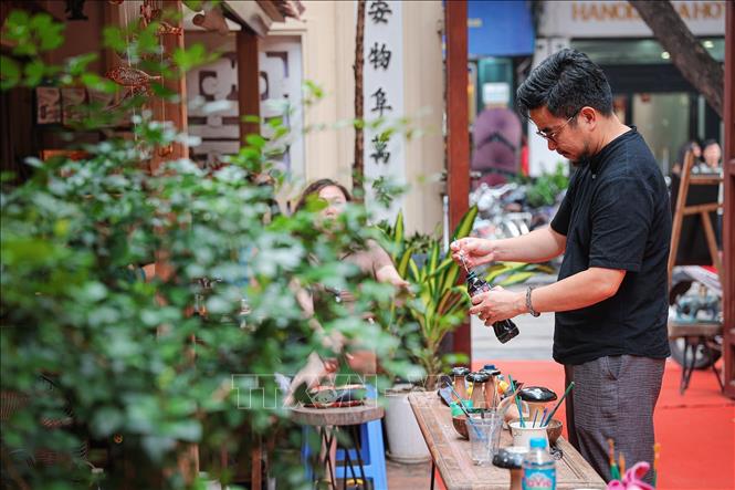 Nghệ nhân ưu tú Nguyễn Tấn Phát chuẩn bị nguyên liệu sơn, giới thiệu các công đoạn chế tác truyền thống trong không gian trải nghiệm mở. Ảnh: Phạm Tuấn Anh - TTXVN
