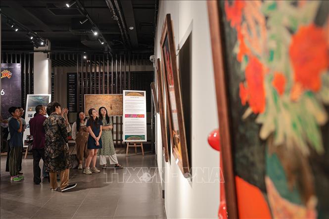 Khách tham quan đang được giới thiệu về những tác phẩm được trưng bày tại triển lãm. Ảnh: Phạm Tuấn Anh - TTXVN