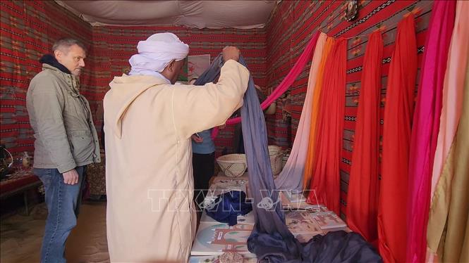 Du khách người Đức xem các sản phẩm khăn choàng đầu của người Hồi giáo địa phương. Ảnh: Mạnh Hùng – PV TTXVN tại Algeria