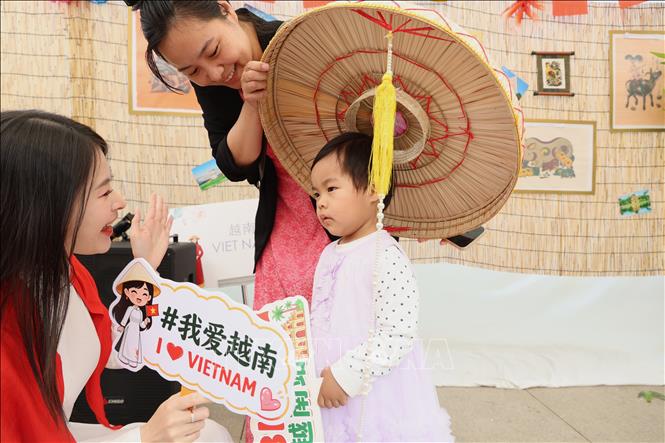Bạn nhỏ được mẹ là người Việt dẫn đến tìm hiểu về văn hóa Việt Nam. Ảnh: Quang Hưng - PV TTXVN tại Trung Quốc