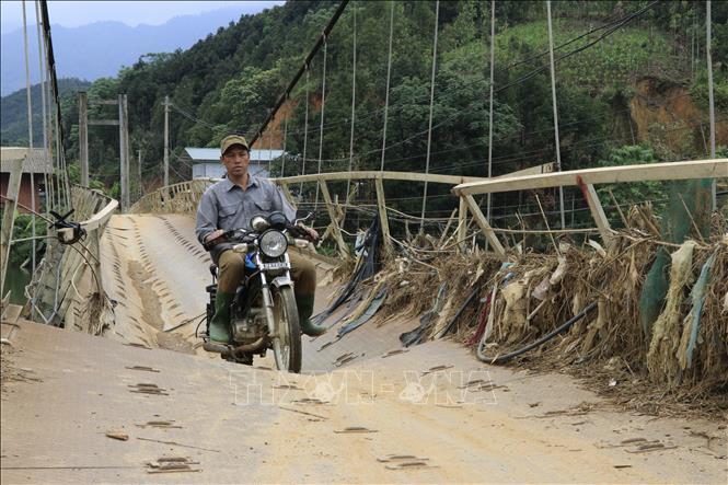 Tuy ý thức rõ ràng sự nguy hiểm, nhưng vì đây là cây cầu độc đạo nên người dân vẫn liều mình hàng ngày đi qua cầu treo này. Ảnh: Anh Thùy - TTXVN