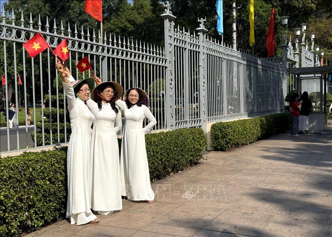 Nhiều gia đình, giới trẻ trang bị thêm cờ hoa để chụp ảnh lưu niệm trong ngày nắng đẹp dịp lễ truyền thống của dân tộc. Ảnh: Thanh Vũ-TTXVN
