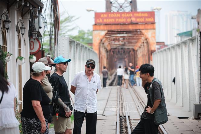 Tourists listen to a local guide introduces Long Bien bridge - a landmark with historical significant to Hanoi. VNA Photo: Phạm Tuấn Anh